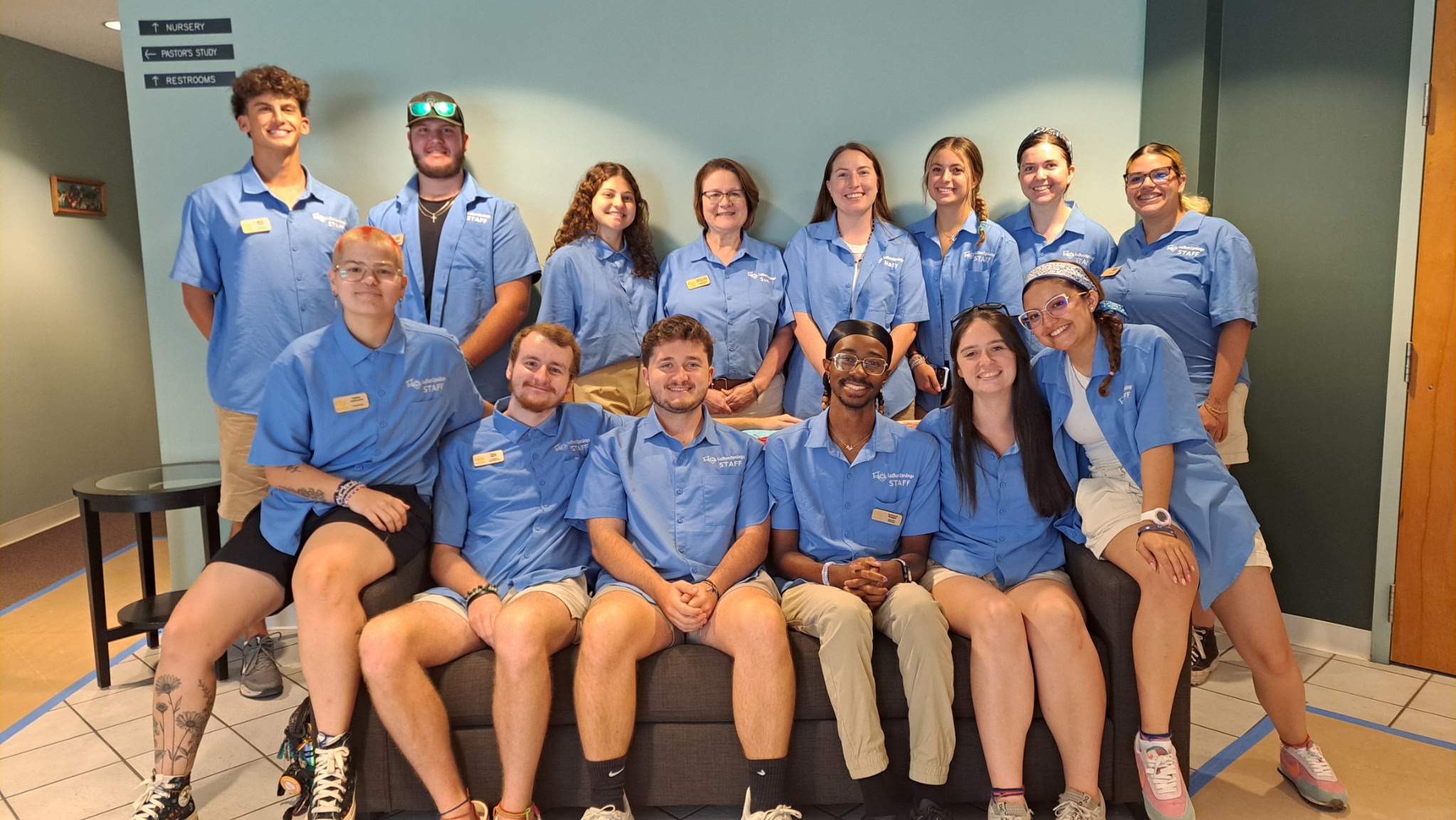 14 Young Adults wearing matching blue Luther Springs Staff shirts are pictured in the Narthex of Gethsemane Lutheran Church on July 5th.